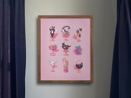 Room interior with a pink cats and cocktails framed artwork on the wall, a record player, and speakers.